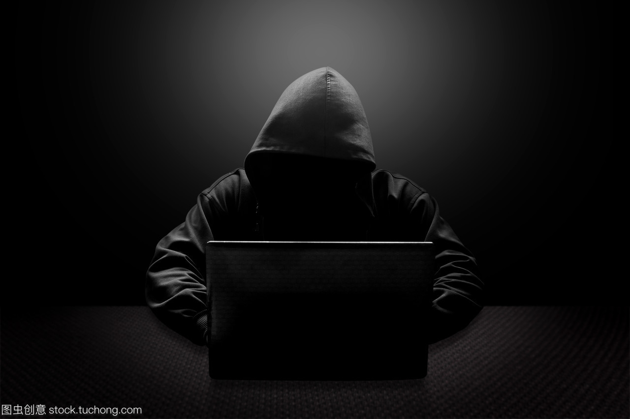 戴兜帽的电脑黑客窃取信息的笔记本电脑